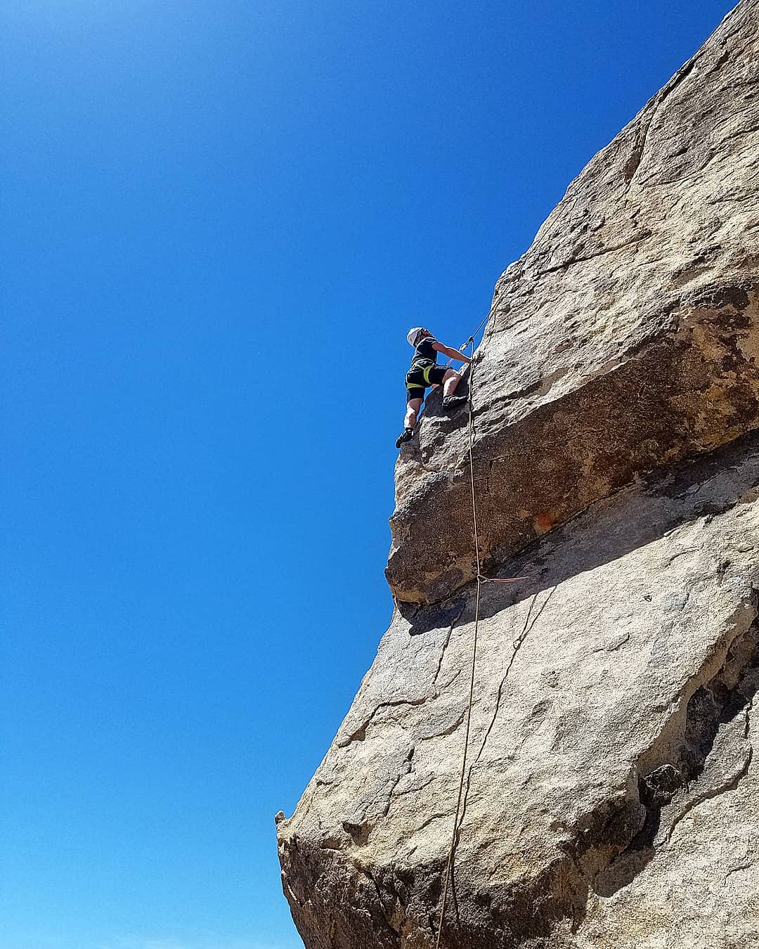 Climbing into to clear blue sky on the "Headstone" formation in Joshua Tree.The "SouthWest Corner, 5.6" might be one of the most photographed rocks/climbs in the park. A striking exposed line starts with a traverse directly to the arête of the SW corner....#chillinorockclimbing #rockclimbing #climbing_pictures_of_instagram #guide #guiding #climbing #optoutside #joshuatree #neverstopexploring...@nilsr_13 @joshuatreenps @thecosmicclimber